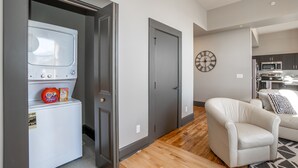 A compact living space with a washing machine, a door, a clock, and a sofa.