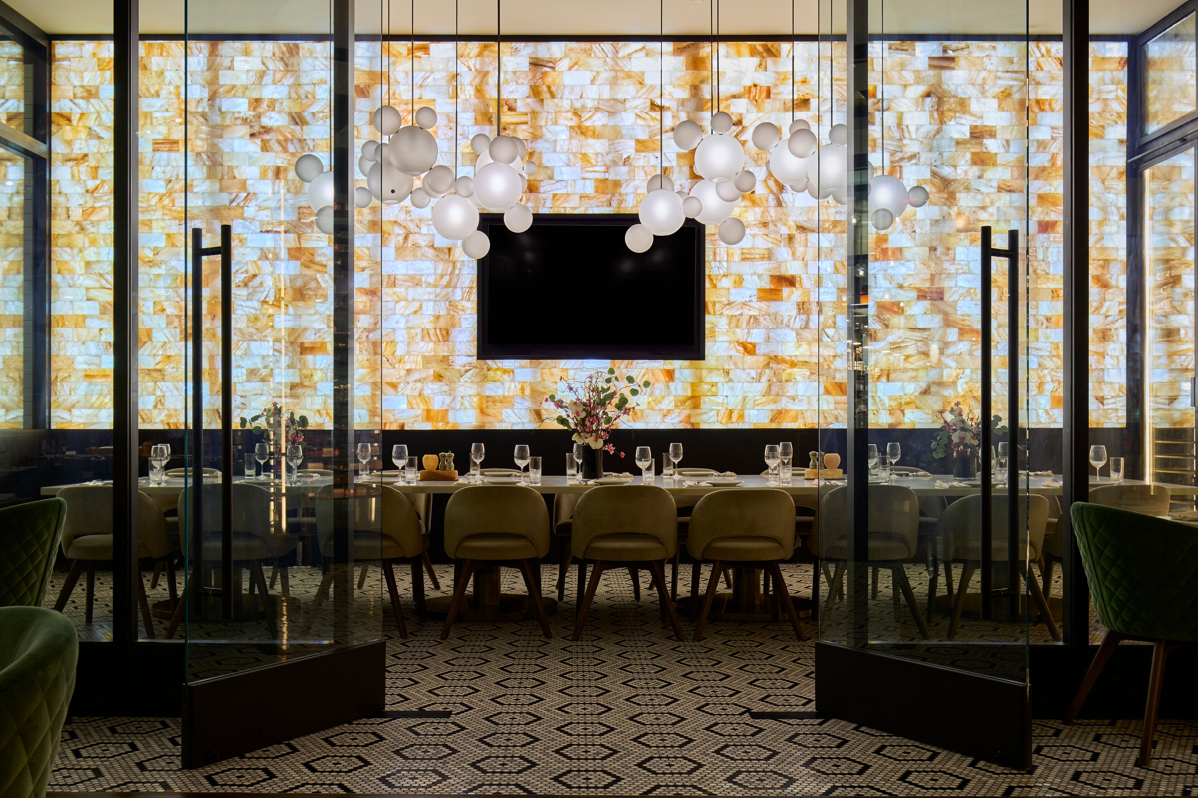 A modern dining area with a large TV screen, glass partitions, and a patterned floor.