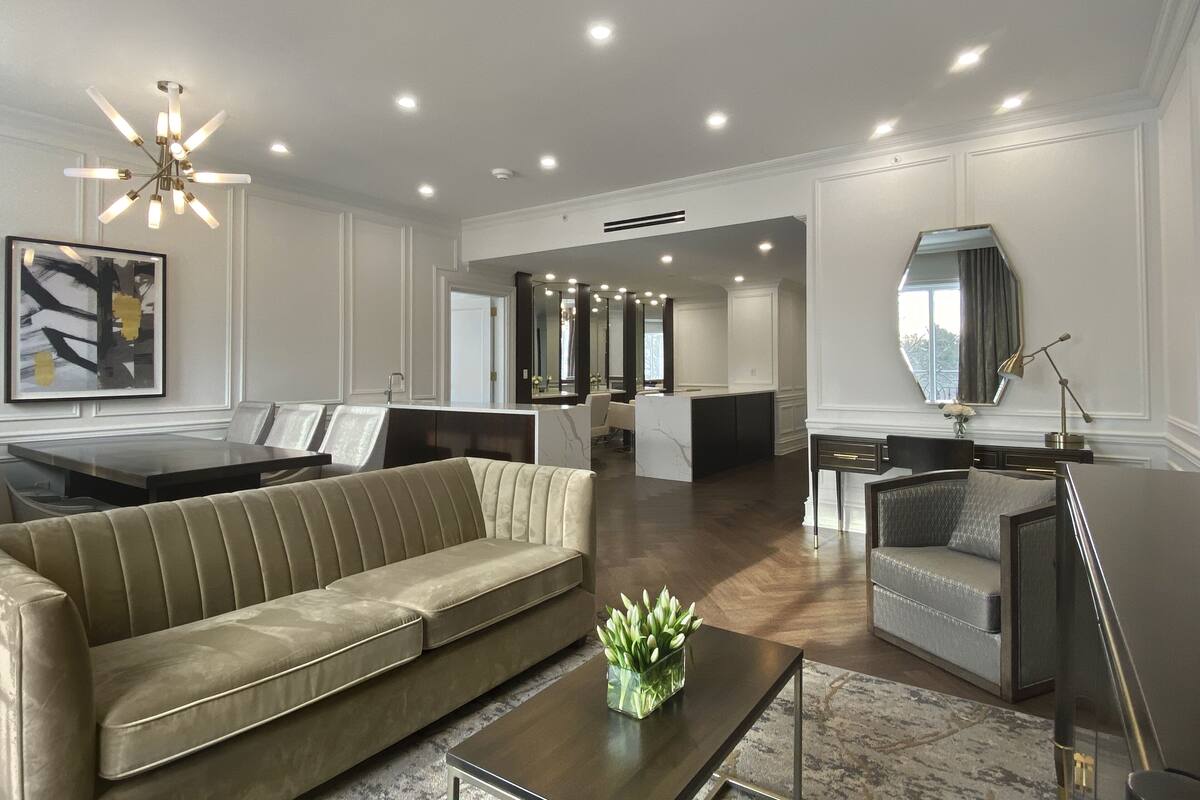 A modern living room with a sofa, coffee table, and a dining area with a table and chairs.