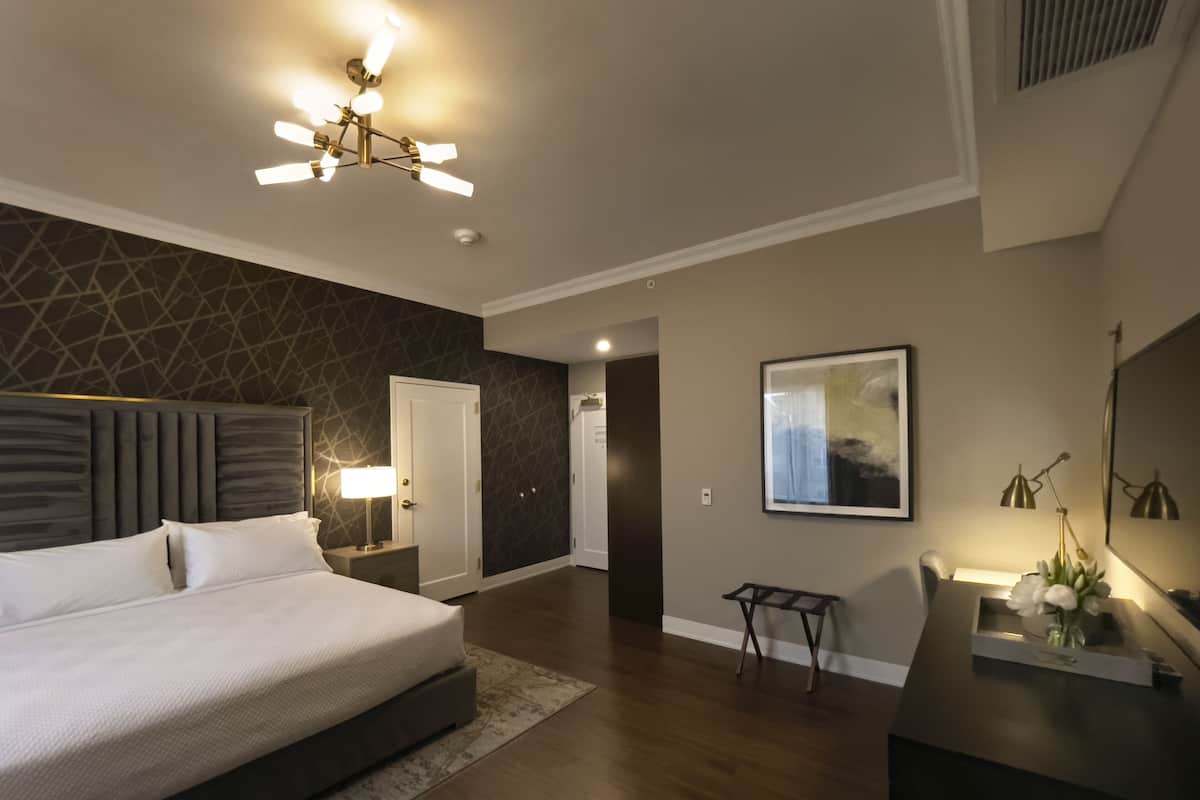 A modern bedroom with a large bed, bedside tables, a desk, and a chair.