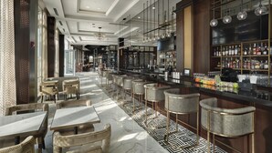 Eine moderne Bar mit einer langen Theke, Barhocker und einer Auswahl an Flaschen und Gläsern.