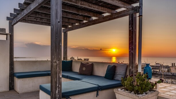 A rooftop seating area with blue cushions and a potted plant. - Mare Mare Mare (Gallipoli)