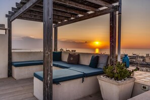 A rooftop seating area with blue cushions and a potted plant. - Mare Mare Mare (Gallipoli)