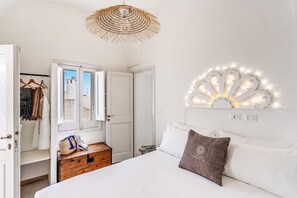 Un dormitorio con cama, lámpara colgante, armario y un pequeño cofre de madera.