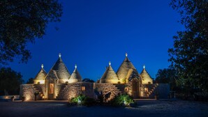 Ein Steinhaus mit mehreren kegelförmigen Dächern, einem zentralen Eingang und einem gepflasterten Innenhof.