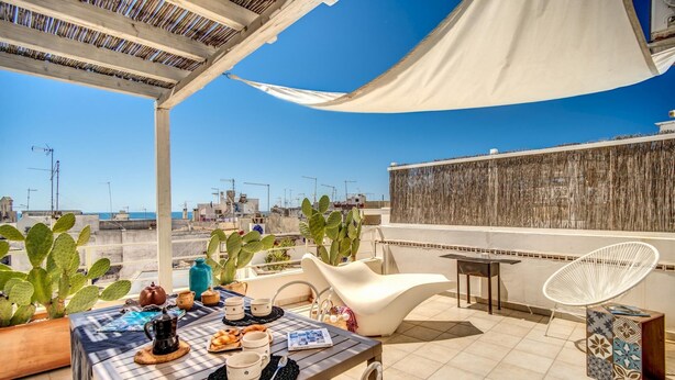 A rooftop terrace with a table set for breakfast, a white chair, and a cactus plant. - Il Nido Gallipoli (Gallipoli)