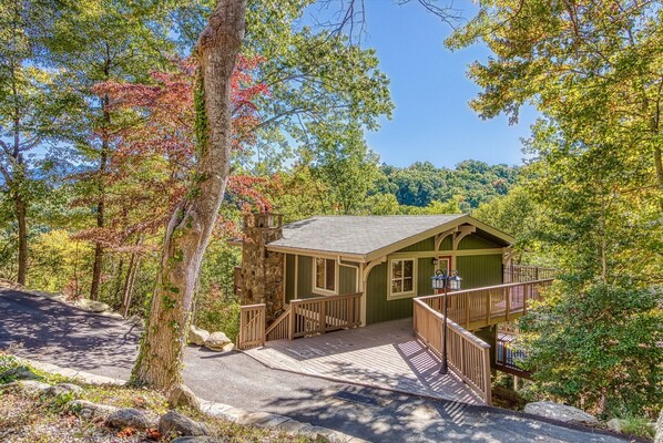 Une petite cabane avec des fondations en pierre, une terrasse en bois et un porche doté de balustrades.