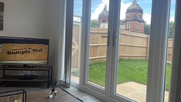 A room with a large sliding glass door leading to a backyard with a wooden fence and a brick building with domed roofs.