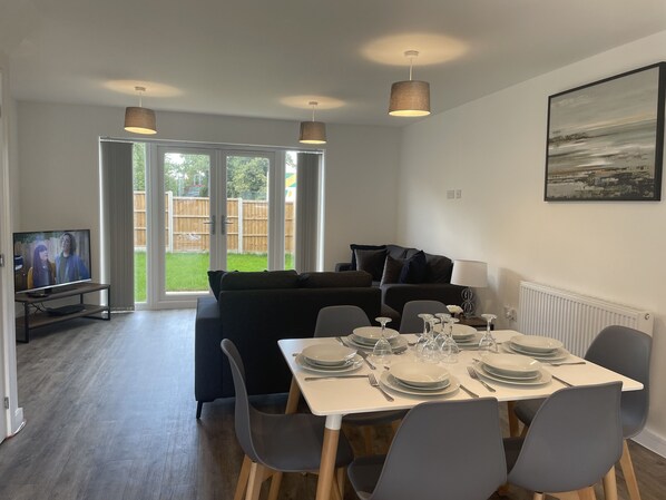 A dining area with a table set for six, a sofa, and a TV in the background.