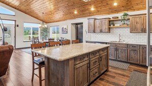 Una cocina amplia con armarios de madera, una isla de granito y un comedor con sillas.