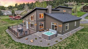Una casa moderna de dos pisos con terraza, mobiliario exterior y jacuzzi.
