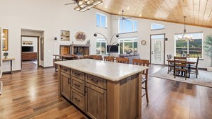 Una cocina amplia con una isla grande, techo de madera y un comedor con mesa y sillas.