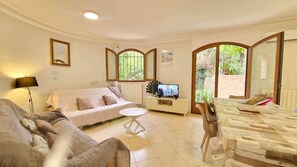 A living room with a sofa, a coffee table, a TV, and a dining area with a table and chairs.