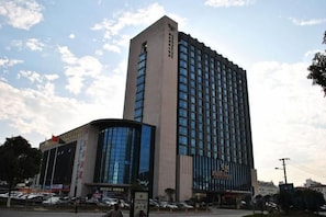 A tall, modern building with a prominent entrance and signage. - Guanfa Enjoy Hotel (Quzhou)