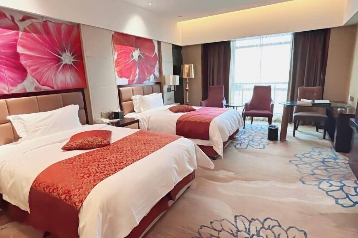 A hotel room with two beds, a desk, and a chair.