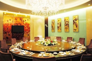 A conference room with a round table, chairs, and a chandelier. - Guanfa Enjoy Hotel (Quzhou)