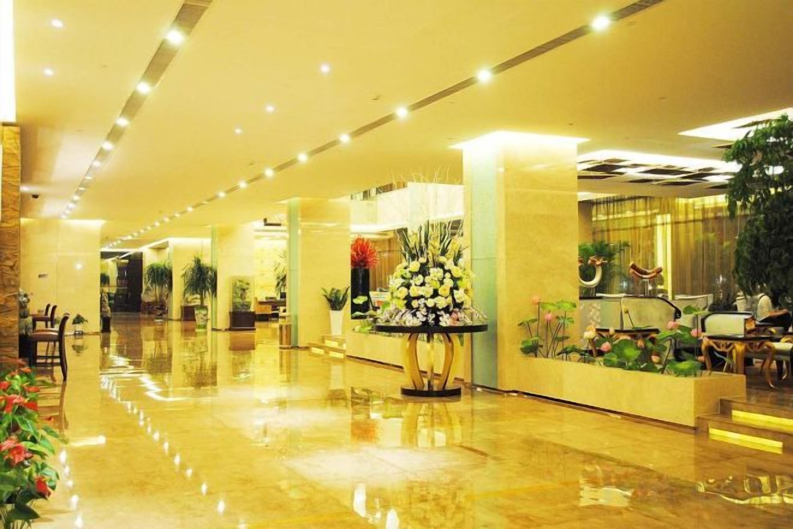 A hotel lobby with a polished floor, seating areas, and decorative plants.