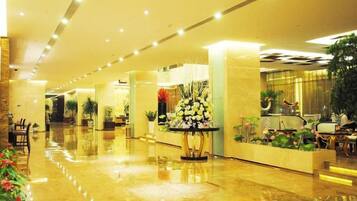 A hotel lobby with a polished floor, seating areas, and decorative plants.