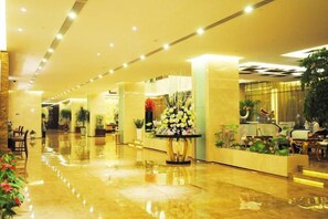 A hotel lobby with a polished floor, seating areas, and decorative plants. - Guanfa Enjoy Hotel (Quzhou)