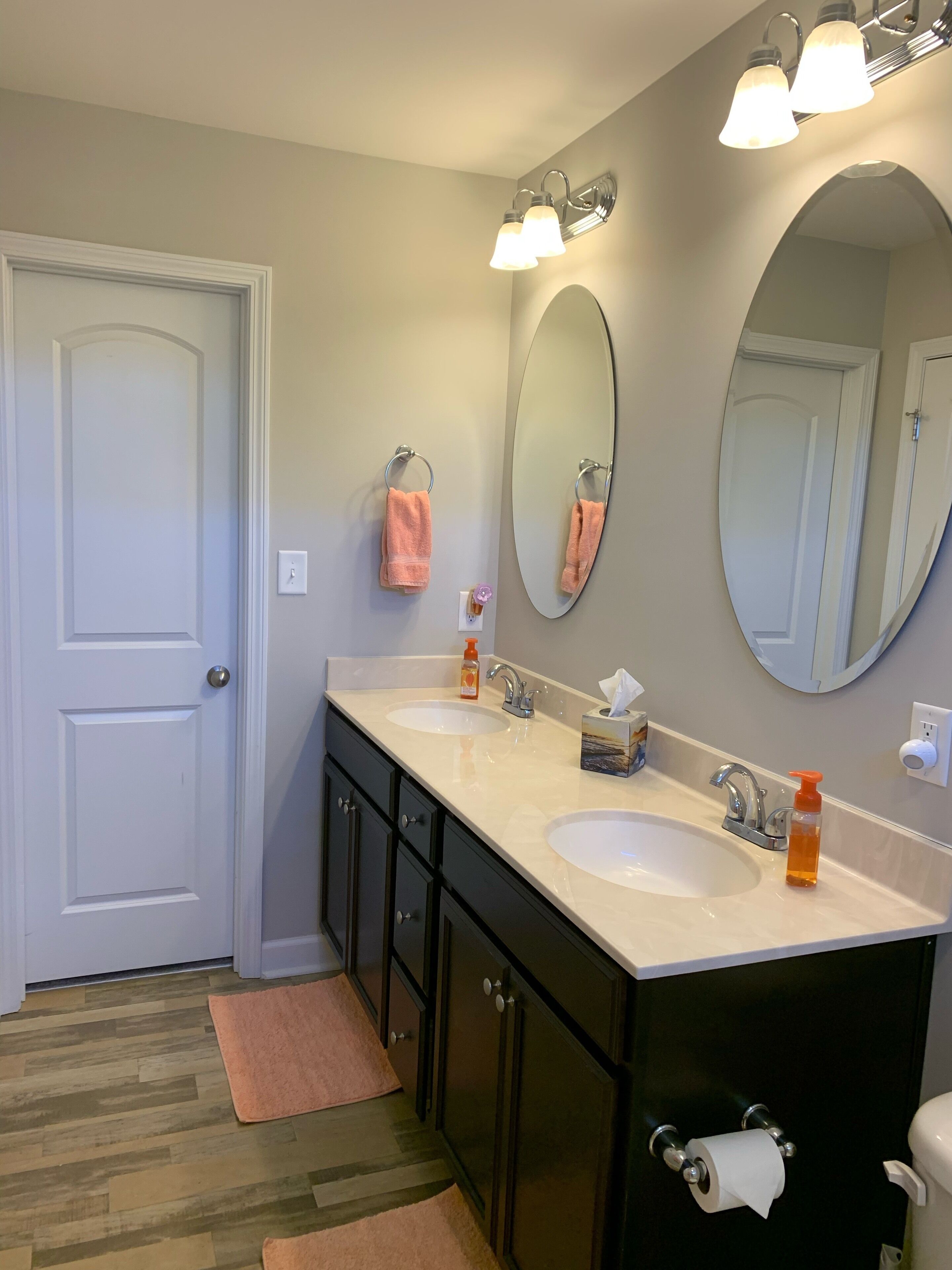 A bathroom with two sinks, a large mirror, and a door.