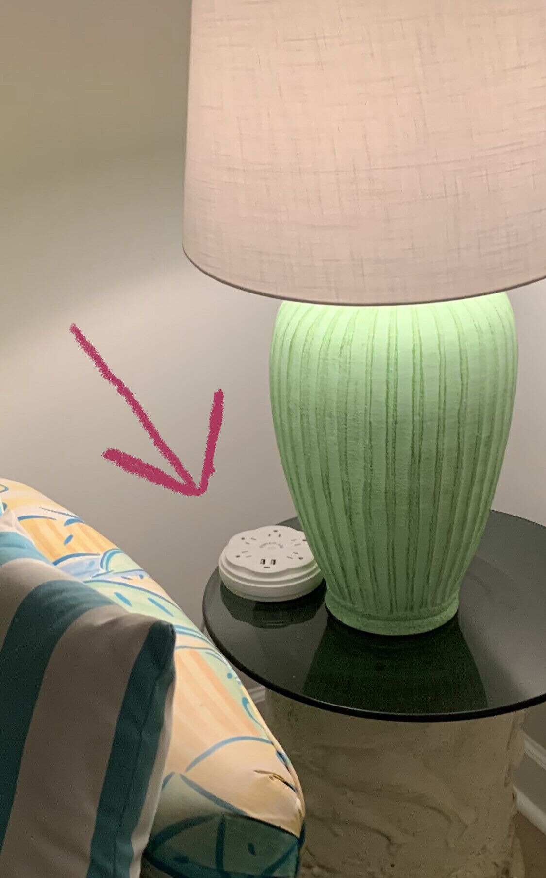 A lamp with a green base and a beige lampshade on a black table.