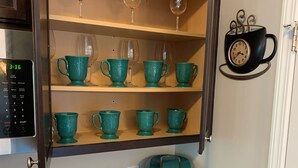 Une cuisine équipée d’une machine à café, de boîtes à thé et d’une horloge murale.