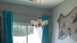Un coin repas avec des chaises de couleur turquoise, une table ronde et un lustre.