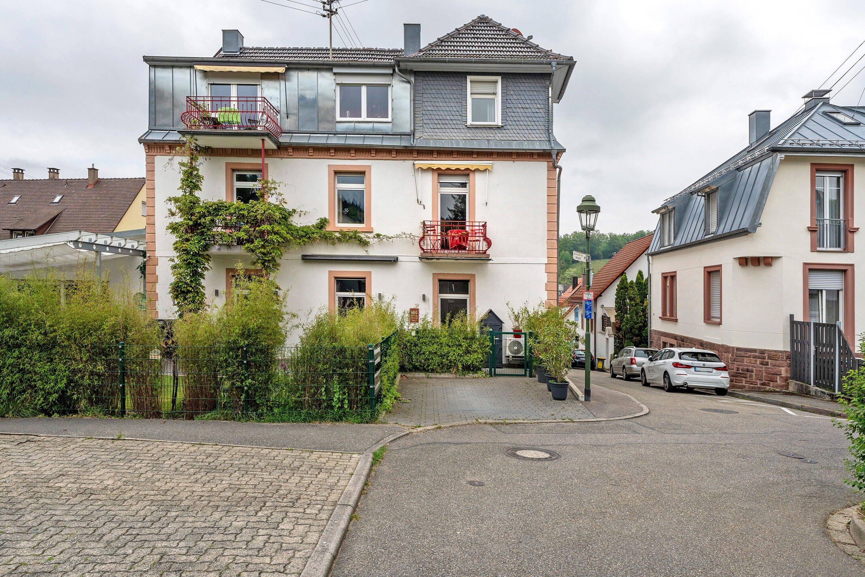 A two-story residential building with a balcony, a garage, and a driveway.