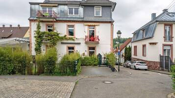 A two-story residential building with a balcony, a garage, and a driveway.