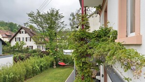 Un barrio residencial con una casa de techo rojo, un jardín con una hamaca y un sendero que conduce a la casa.