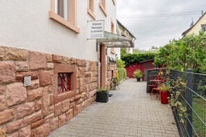 A narrow alleyway with a stone wall, a glass door entrance, and potted plants. - Pet-Friendly Holiday Apartment 'Lichtentaler Allee' with Balcony and Wi-Fi (Baden-Baden)