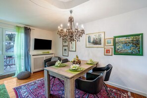En matplats med en kristallkrona, en tv, inramade konstverk och ett bord dekorerat med en mittuppsättning.