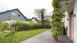 A residential area with a wooden deck, a grassy lawn, and houses in the background.
