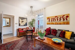 A living room with a sofa, chairs, a coffee table, a rug, and artwork on the walls.