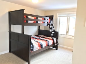 A bunk bed with a ladder in a room with a window and a door.