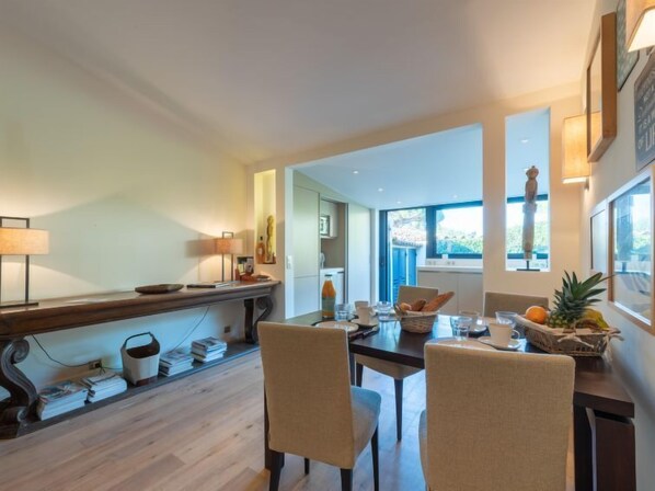 A dining area with a wooden table, chairs, and a view of the outdoors.
