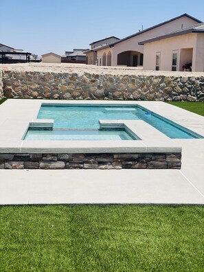 Une piscine rectangulaire agrémentée d’éléments en pierre et dont le fond est constitué d’un mur en pierre.