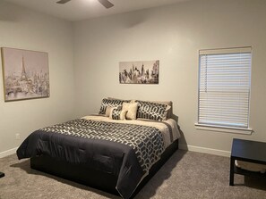 Une chambre à coucher avec un lit, une table de chevet et deux tableaux accrochés au mur.
