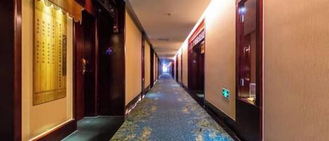 A hotel hallway with a patterned carpet, wooden doors, and a traditional design.