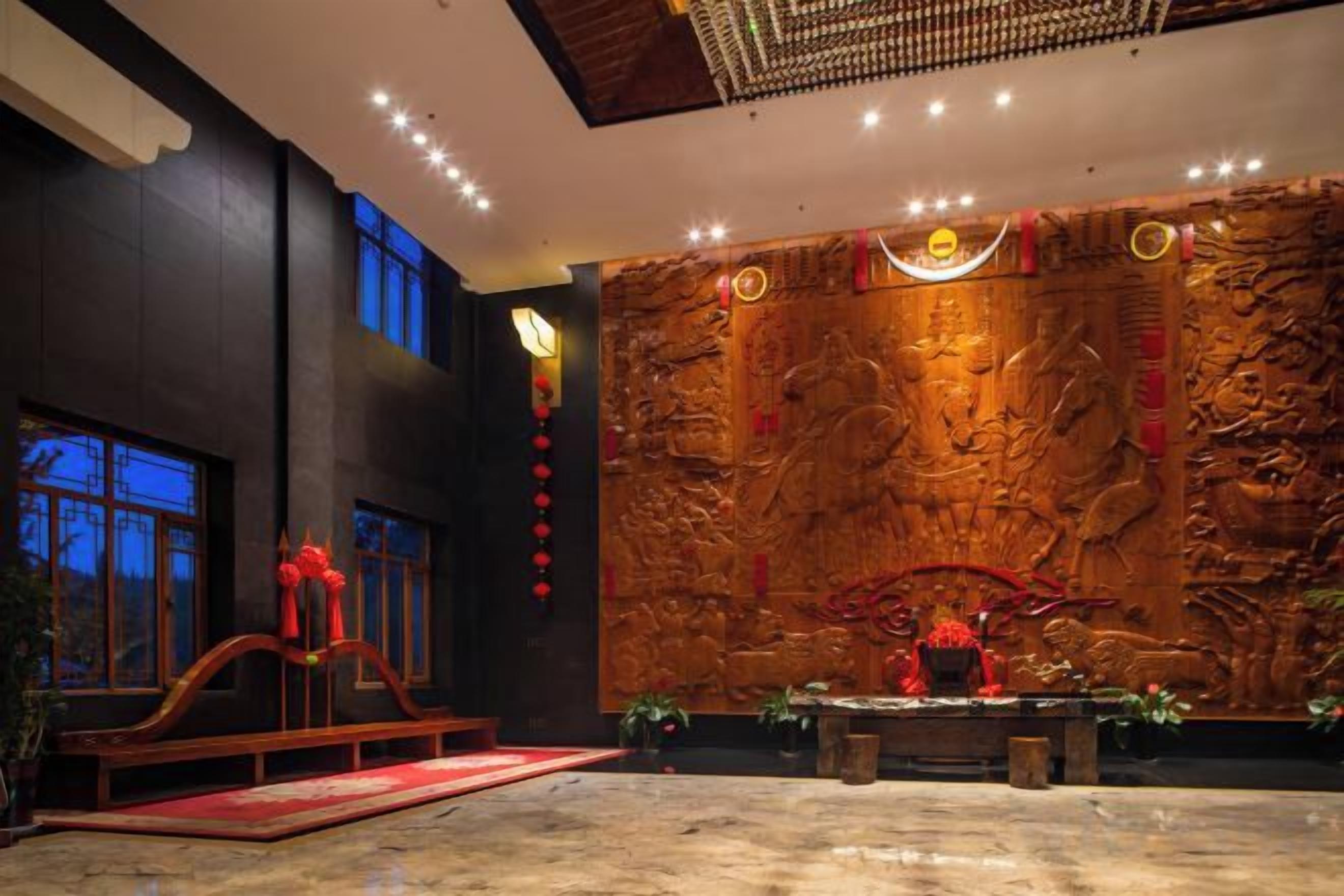Una habitación con un mural grande en la pared, un altar de madera y un adorno rojo.