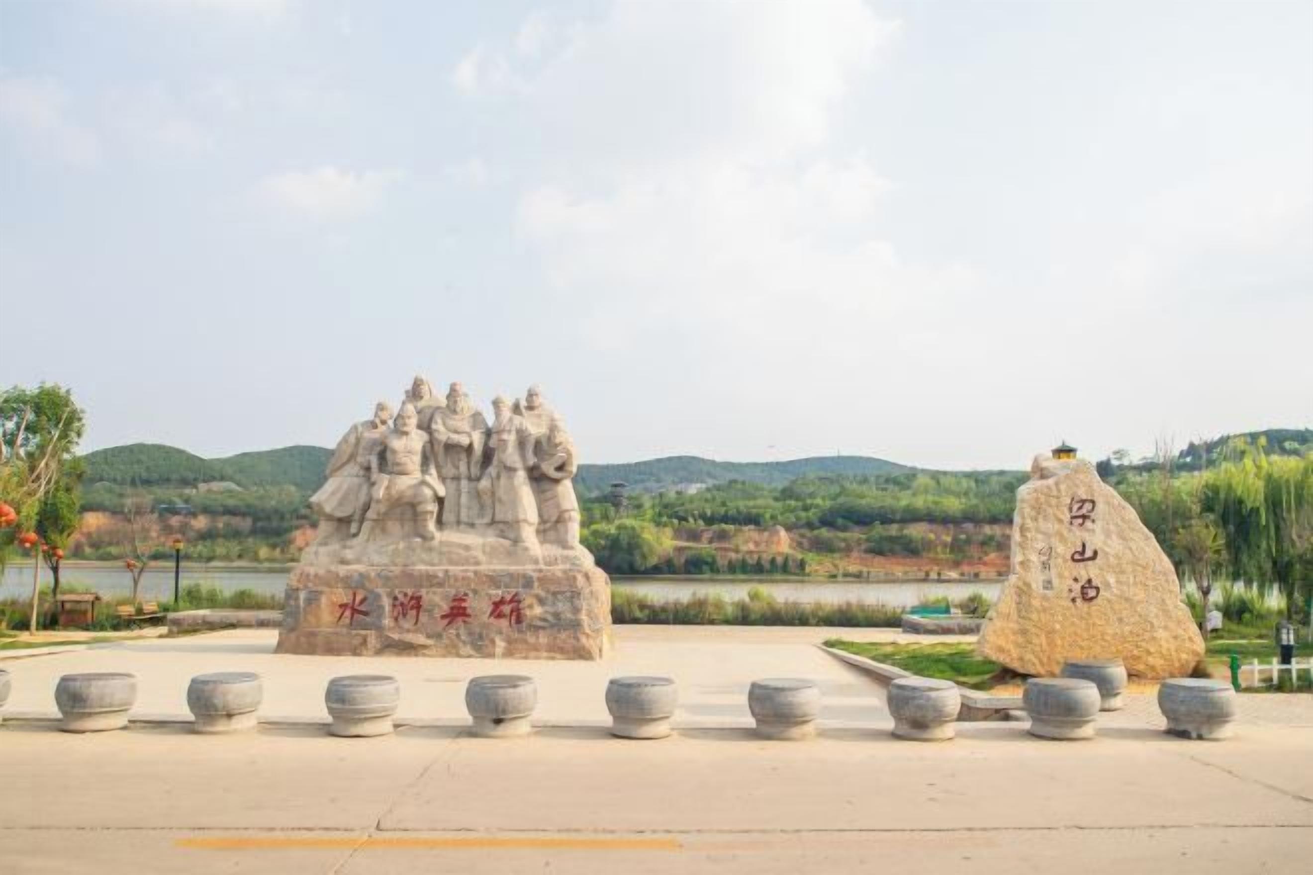 Een stenen monument met inscripties, een grote rots met Chinese karakters, en een prachtig uitzicht op heuvels en een meer.