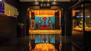 Un hall d’hôtel doté d’un sol réfléchissant, d’un comptoir d’accueil et d’un mur décoratif aux couleurs rouge et or.
