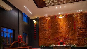 Un intérieur traditionnel avec un grand mur en bois sculpté, un banc en bois et des décorations rouges.