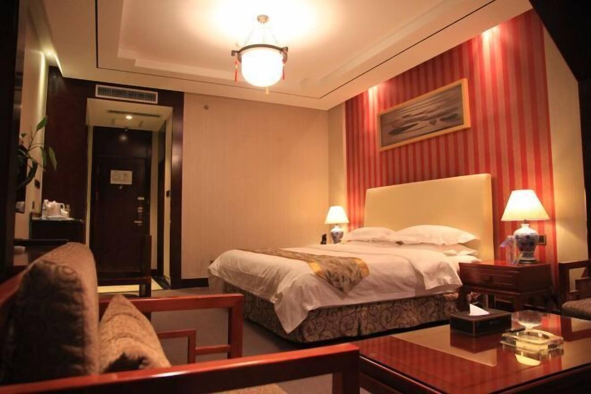 A hotel room with a bed, bedside lamps, a desk, and a chair.