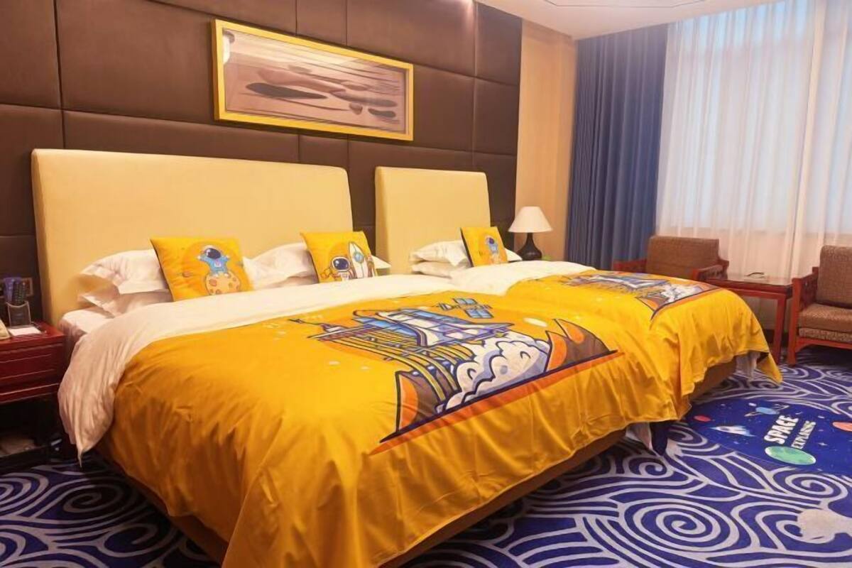 A hotel room with two beds, a large painting on the wall, a chair, and a patterned carpet.