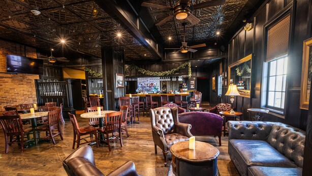 A bar area with wooden tables, leather seating, and a bar counter. - The Inn at Elijah McLeans (Washington)