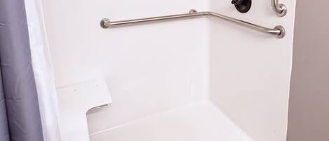 A shower with a grab bar, a shower curtain, and a metal handrail.