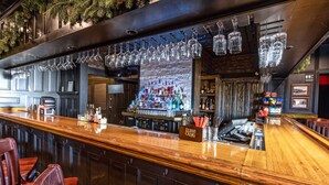 A bar area with a wooden counter, hanging glasses, and a liquor display. - The Inn at Elijah McLeans (Washington)