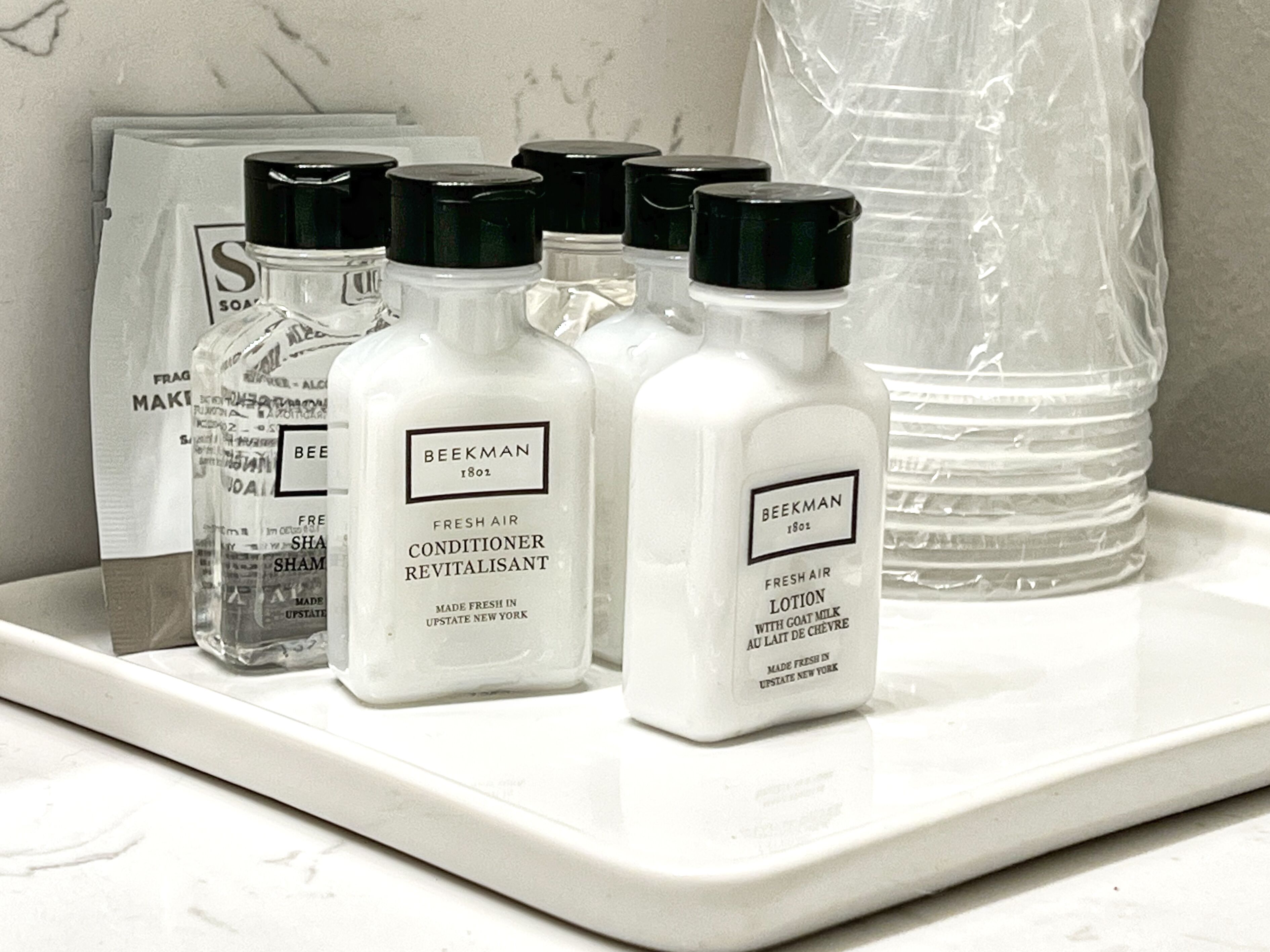 A tray with several bottles of Beekman Fresh Air Conditioner Revitalisant and Fresh Air Lotion, along with other toiletries.