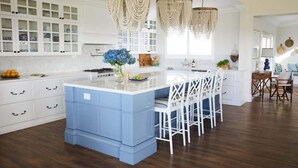 A spacious kitchen with a large island, white cabinetry, and a blue accent wall. - Hamptons Farm Estate—Luxe Retreat & Elegant Events (Wongamine)